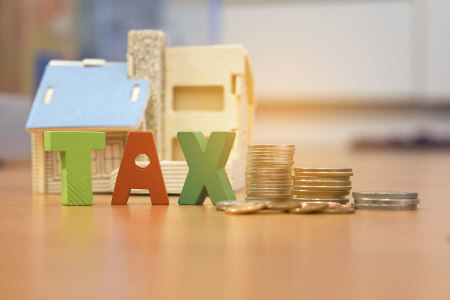 Tax sign with model house and coins